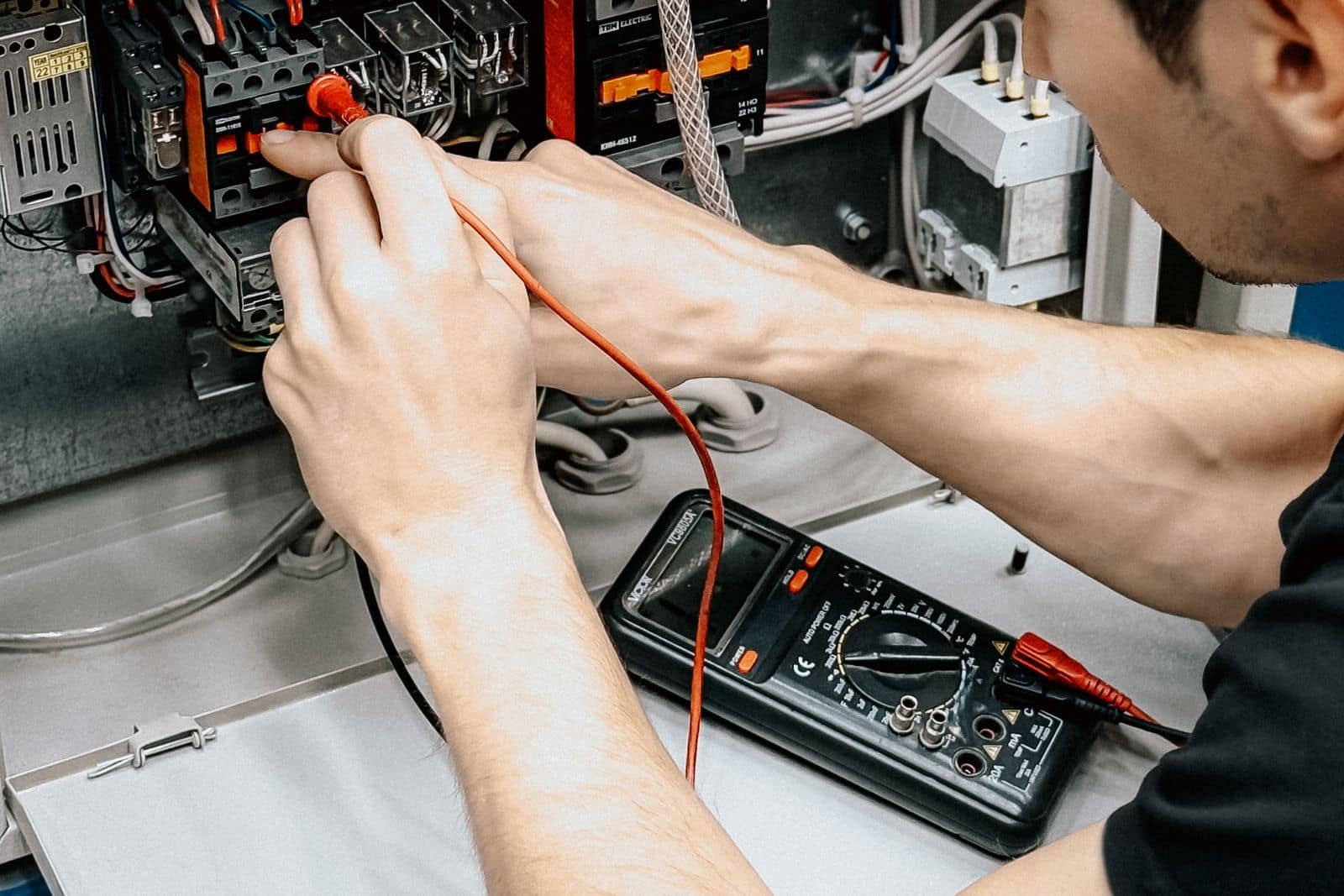 Electrician diagnosing an electrical panel with a multimeter