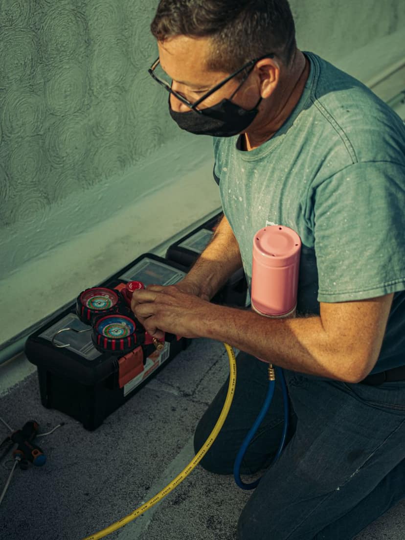 HVAC technician kneeling to service equipment on a job